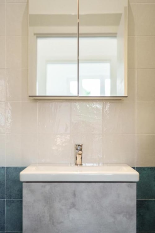 Bagno moderno a IL POETA Procida con lavabo bianco, piastrelle color crema e grande specchio con vista sui monumenti