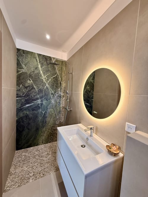 Salle de bains moderne de la villa Figari avec miroir ovale illuminé, lavabo blanc et douche en marbre noir