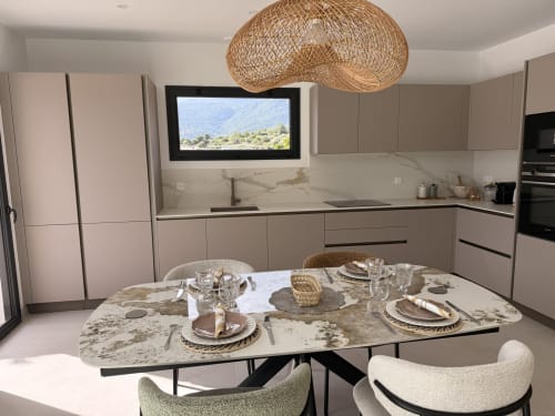 Cuisine ouverte et salle à manger de la villa Figari avec table en marbre, luminaire suspendu tressé et vue sur les montagnes