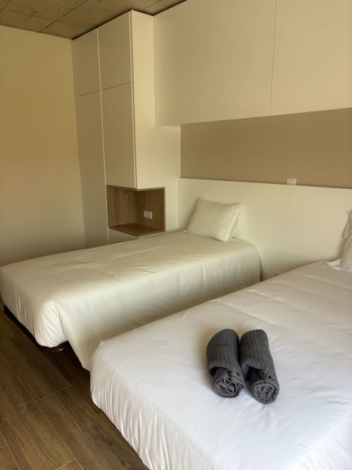 Quarto moderno do AL Patio Da Figueira com camas twin, roupa de cama creme, toalhas enroladas e paredes minimalistas bege em Torres