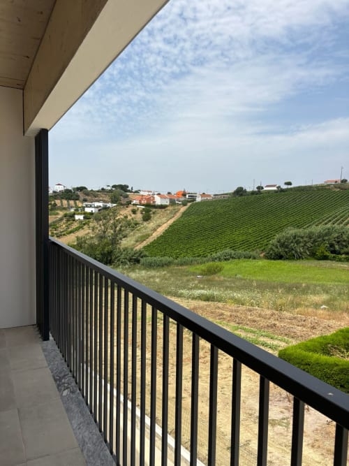 Vista da varanda com paisagens de vinhedos e edifícios rurais do hotel AL Patio Da Figueira em Torres Vedras, Portugal