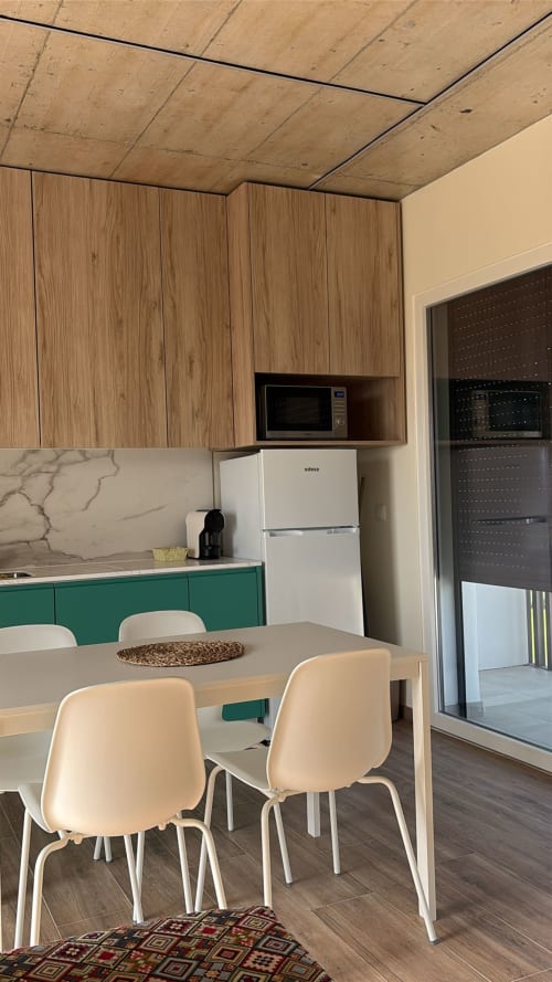 Área de cozinha-sala de jantar moderna no AL Patio Da Figueira com armários de madeira, móveis verdes, eletrodomésticos brancos e mesa de jantar