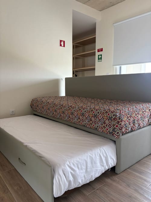 Quarto limpo com cama de estrutura branca, roupa de cama estampada e cabeceira cinzenta no hotel AL Patio Da Figueira em Torres Vedras