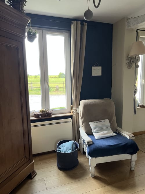 Chambre cosy au Domaine De La Ferme De Ribeaufontaine avec mur bleu, lit blanc, vue sur le lac et style rustique
