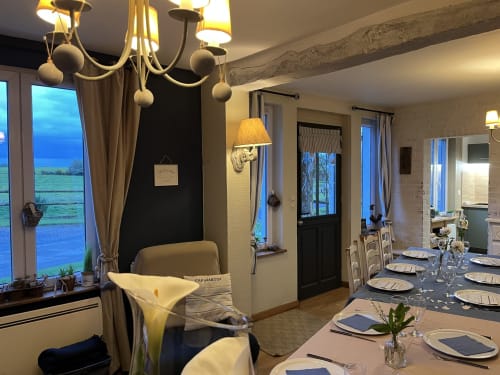 Élégante salle à manger du Domaine De La Ferme De Ribeaufontaine avec vue sur le lac, lustre et table dressée
