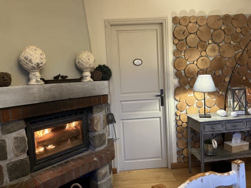 Salon douillet avec foyer, décoration murale en tranches de bois et lampe au Domaine De La Ferme De Ribeaufontaine à Dorengt, France