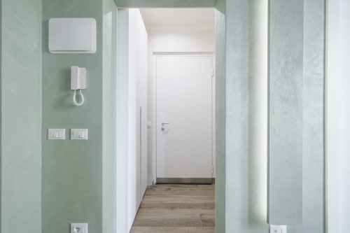Modern apartment entrance hallway with sage green walls, white door, and wooden flooring at STAYIN VERONA hotel