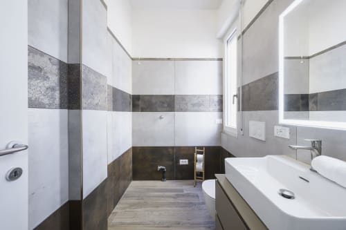 Modern bathroom with white and gray tiled walls, walk-in shower, dual sink vanity, and heated floors at STAYIN VERONA