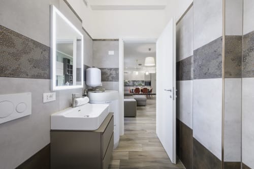 Modern bathroom in Arena Gateway apartment at STAYIN VERONA, featuring sink with mirror, tiled walls, and view to living