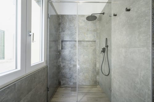 Modern glass-enclosed shower with gray tile walls and rainfall showerhead at STAYIN VERONA apartment in Verona