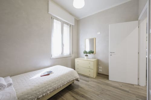 Modern bedroom in Verona apartment with single bed, yellow dresser, mirror, and wooden flooring