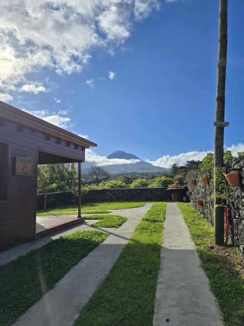 Mountain Wood Village apartment pathway with landscaped gardens, stone walls, and volcano views in Madalena