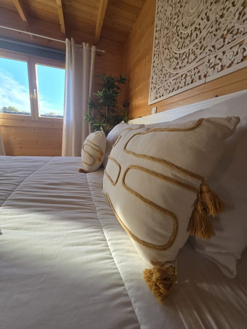 Luxurious bedroom at Mountain Wood Village B, Madalena, featuring cream pillows with gold trim, wooden ceiling, decorative
