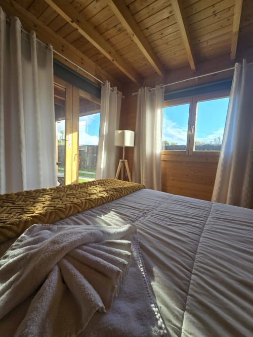 Sunny bedroom at Mountain Wood Village B in Madalena with wooden beams, twin beds, white curtains and mountain views