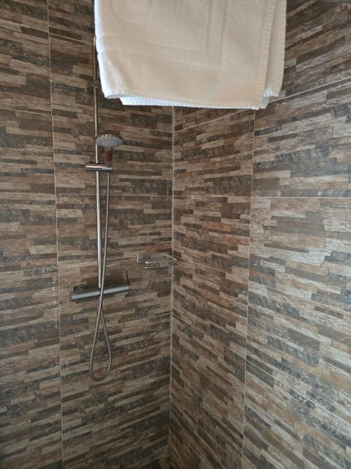 Modern shower at Mountain Wood Village B apartment in Madalena with wood-look tile walls and rainfall showerhead