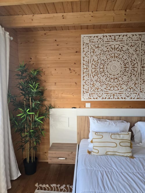 Cozy wooden bedroom at Mountain Wood Village in Madalena with carved panel art, plant, and white bedding