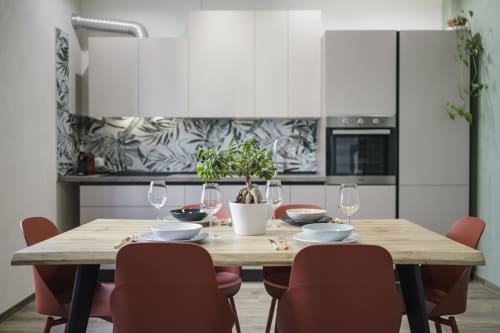 Modern kitchen-dining area at STAYIN Verona with wooden table, burgundy chairs, and botanical-patterned backsplash