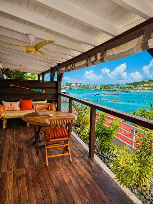 Balcon tropical aux Balcons D'Oyster Pond avec vue sur la mer des Caraïbes turquoise, terrasse en bois, table à manger et ventilateur de plafond