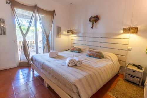 Habitación luminosa en Urban Beach Rentals, Albufeira con cama doble, balcón con vista al jardín y ropa de cama a rayas