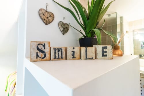 Bloques de madera con la palabra 'SMILE' en estante con planta decorativa, corazones y detalles en cobre en Urban Beach Rentals