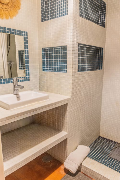 Baño moderno con revestimiento de azulejos en tonos crema y azul, lavabo, espejo y ducha de obra en apartamento Urban Beach Rentals, Albufeira