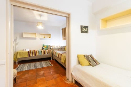 Dormitorio luminoso en apartamento de Albufeira con camas gemelas, detalles amarillos y sala común con muebles a rayas
