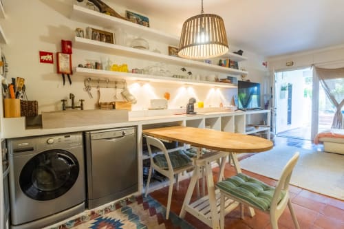 Moderna cocina y comedor en apartamento de Albufeira con electrodomésticos de acero inoxidable, estanterías blancas y mesa de comedor de madera