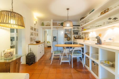 Moderna cocina de apartamento con zona de comedor, estanterías blancas, mesa de madera y pisos de terracota en Urban Beach Rentals