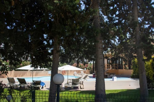 Área de piscina en Urban Beach Rentals de Albufeira con tumbonas, sombrillas y árboles frondosos que proporcionan sombra