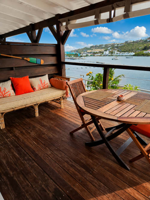 Terrasse avec vue sur le port de Saint-Martin aux Balcons d'Oyster Pond, mobilier en bois et coussins corail