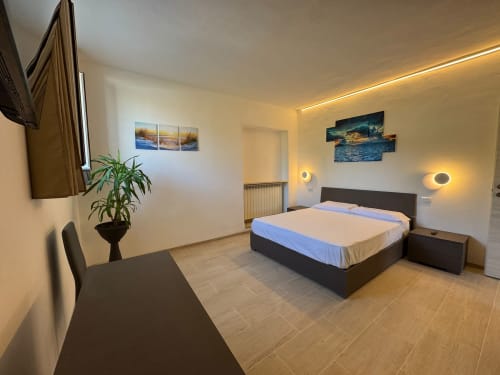 Camera Elisabetta al Queen Hotel di Campofilone: camera moderna con letto matrimoniale, scrivania, illuminazione calda e arredamento contemporaneo