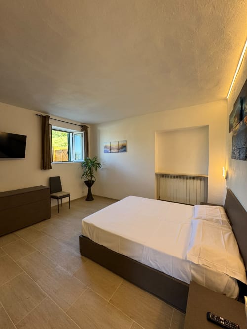 Ampia camera Elisabetta del Queen Hotel a Campofilone con letto, TV, finestra e servizi moderni