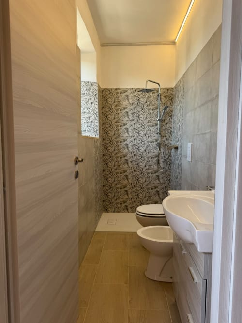 Bagno moderno nella camera Elisabetta dell'hotel Queen a Campofilone, con doccia walk-in, wc, bidet e finiture contemporanee