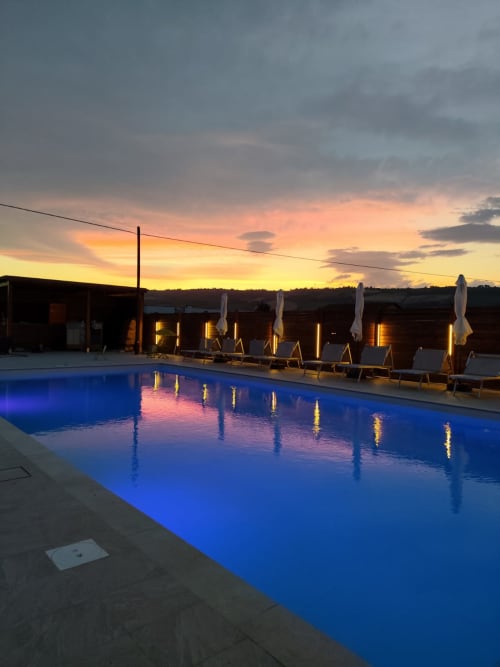 Piscina illuminata al tramonto con lettini e ombrelloni, Queen Hotel Campofilone, vista dalla camera Elisabetta
