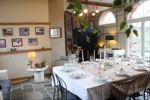Salle à manger élégante du Domaine De La Ferme De Ribeaufontaine avec table dressée, lustre et lumière naturelle des baies voûtées