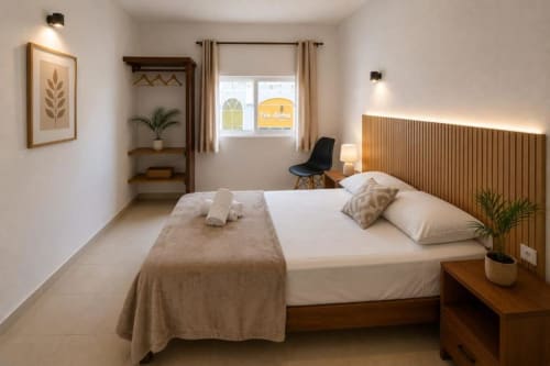 Habitación moderna del Hotel Isla Mujeres Centro con vista al océano, cama de madera, ropa de cama blanca y mobiliario contemporáneo