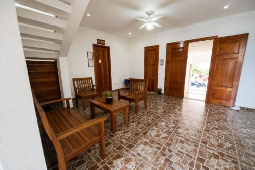 Luminoso vestíbulo de descanso en Hotel Isla Mujeres Centro con sillas de madera, pisos de azulejo y múltiples puertas de madera
