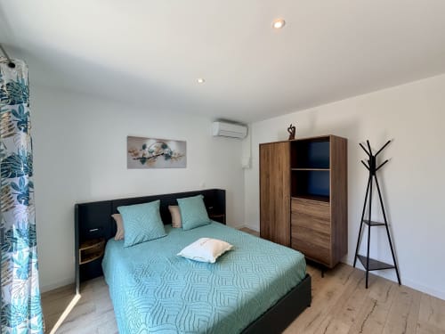 Spacieuse chambre double à la Résidence CARPE DIEM à Lorgues avec literie turquoise, armoire en bois et vue sur le jardin