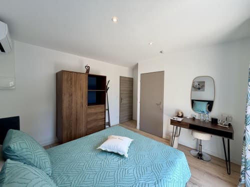 Suite chambre moderne à la Résidence CARPE DIEM : literie turquoise, armoire en bois, coiffeuse et vue sur jardin