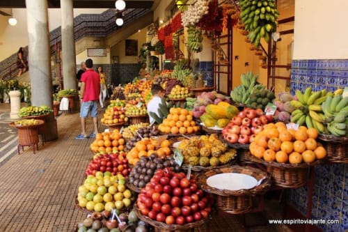 Mercado colorido de frutas e vegetais no Funchal com produtos tropicais, bananas, laranjas e bens locais expostos em cestos