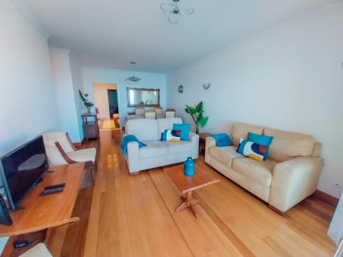 Sala de estar clara do apartamento Casa Delores em Funchal, com sofás brancos, pisos de madeira e detalhes em azul