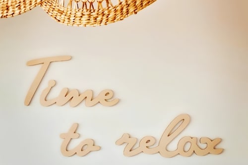 Wooden 'Time to relax' sign with woven basket at Sable & Pampas bed and breakfast in Carnon-Plage