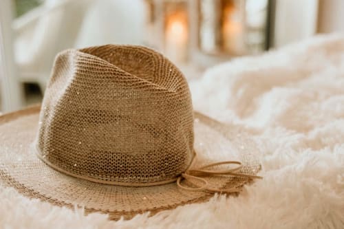 Woven straw hat on plush white bedding at Sable & Pampas, Carnon-Plage beach resort