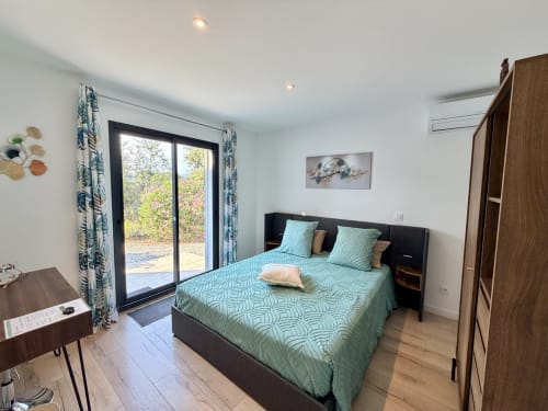 Spacious suite bedroom at CARPE DIEM in Lorgues with turquoise bedding, garden view doors, wooden wardrobe, and modern
