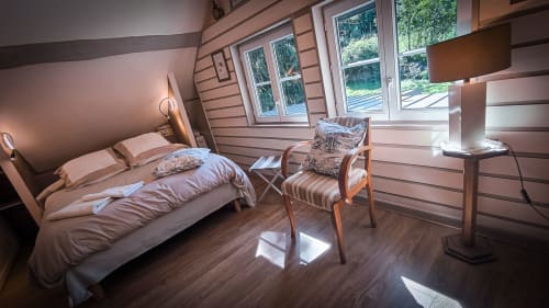 Chambre lumineuse au Clos du Buisson avec lit, fauteuil, parquet et vue sur le jardin