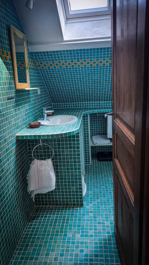 Salle de bains carrelée bleu-vert avec lavabo, toilettes et douche de la Suite Arums au Clos du Buisson