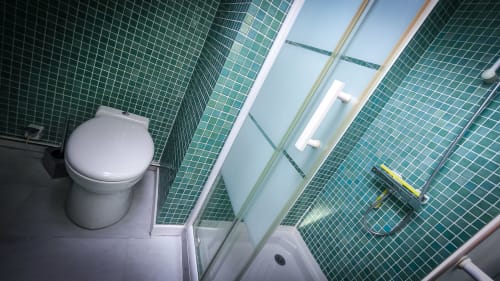 Salle de bain moderne avec carrelage mosaïque vert, toilettes blanches et douche vitrée dans la Suite Arums au Clos du Buisson