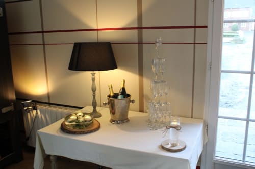 Table élégante au gîte Domaine De La Ferme De Ribeaufontaine à Dorengt avec lampe, vin, verres et amuse-bouches