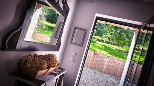 Intérieur lumineux du BnB Le Clos du Buisson avec vue sur jardins paysagés et terrasse en bois par portes ouvertes