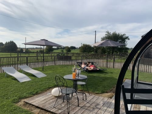 Terrasse extérieure du gîte Domaine De La Ferme à Dorendt avec transats, parasols et vue sur la campagne